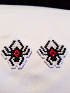 pair of black and white beaded earrings with red eye on them sitting on top of a white cloth