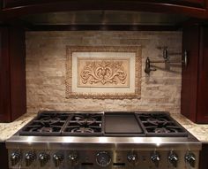 a stove top oven sitting inside of a kitchen next to a wall with a painting on it