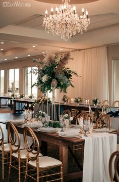 a dining room table set with white linens and gold chairs