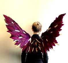 a woman with her back to the camera, wearing a purple and gold wing costume