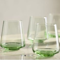 four green glasses sitting on top of a white table next to each other and one is empty