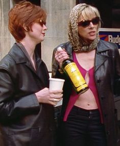 two women standing next to each other holding drinks