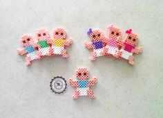 three small cross stitch teddy bears sitting on top of a table next to a button