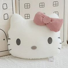 a hello kitty pillow with a pink bow on it's head sitting next to two pillows