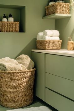 Light sage green bathroom with woven baskets and sage green walls creating a serene storage-smart space