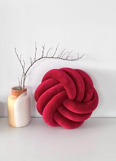 a red ball sitting next to a white vase