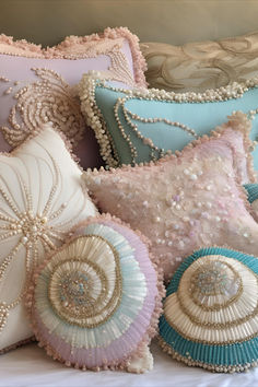 several decorative pillows on a bed with beaded trimmings and sequins