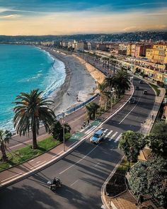 an aerial view of the beach and ocean with cars driving down it's road