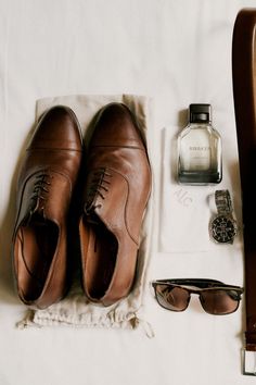 an assortment of men's clothing and accessories laid out on top of a bed