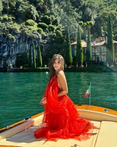 a woman in a red dress is sitting on a boat