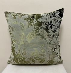 a green and black pillow sitting on top of a white chair