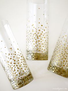 three clear vases with gold polka dots on the bottom, one is empty and two are half full