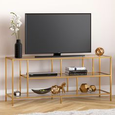 a flat screen tv sitting on top of a metal shelf next to a vase with flowers