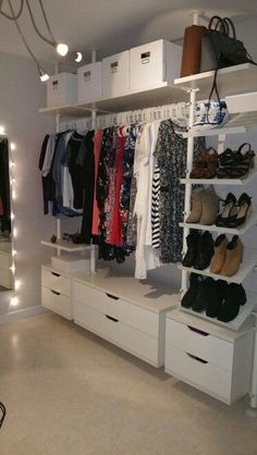 a closet with white drawers and shelves filled with clothes, shoes and handbags