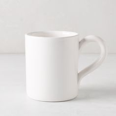 a white coffee cup sitting on top of a table