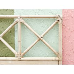 a close up of a bamboo fence against a pink and green wall