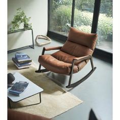 a living room with a rocking chair and large windows