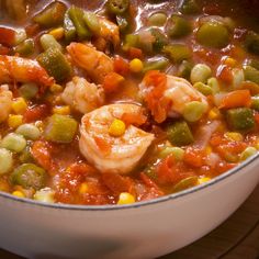 a pot filled with shrimp and vegetables on top of a wooden table