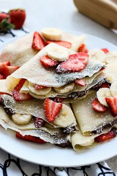 strawberry banana nutella crepes on a white plate