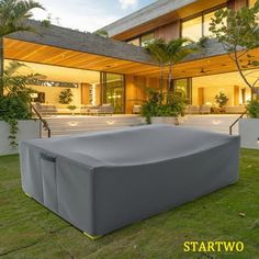 an inflatable sofa sits on the grass near a modern house at night time