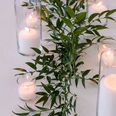 candles and greenery are arranged on the table