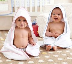 two babies are sitting on the floor wrapped in towels