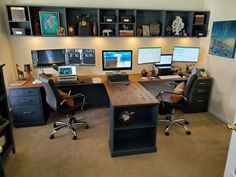 a home office with multiple computer screens and desks on the wall, along with two large bookshelves