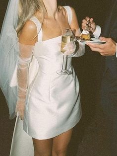 a woman in a white dress holding a plate with food on it and a man in a suit standing next to her