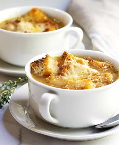 a white cup filled with soup on top of a saucer