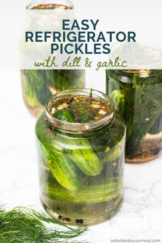 two jars filled with pickles on top of a white counter next to some dilling