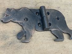 two metal bears that are attached to a door hinge on a wooden surface with holes in the middle