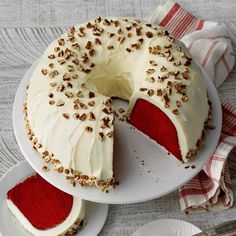 a red velvet cake with white frosting and sprinkles sits on a plate