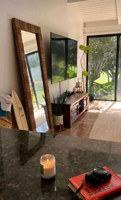 a room with a table, mirror and surfboard on the counter in front of it