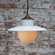 a light that is hanging from a ceiling in front of a brick wall and floor