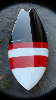 a red and white striped surfboard laying on the ground