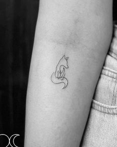 a woman's arm with a small cat tattoo on the left side of her arm