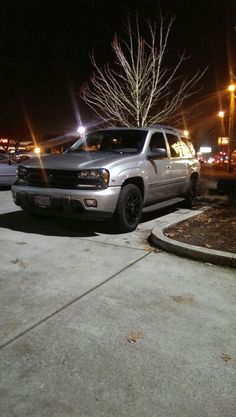 a silver truck parked in front of a parking lot at night with street lights on