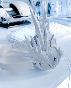 a computer keyboard sitting on top of a white desk next to a paper bird sculpture