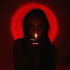 a woman holding a lit candle in front of her face