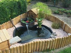 a small pond in the middle of a wooden fenced area with plants and water