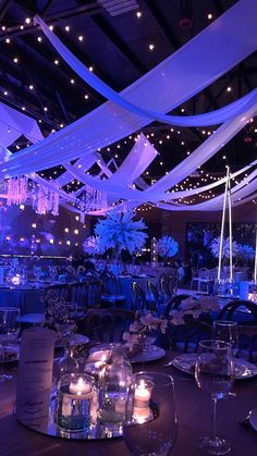 a banquet hall with blue lighting and white draping on the ceiling is set up for an event