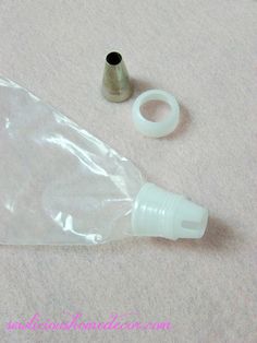 an empty plastic bottle sitting on the floor next to a small metal tube and thread