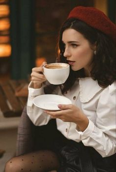 a woman sitting on a bench holding a cup of coffee