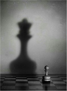 a black and white photo of a chess board with the shadow of a pawn on it