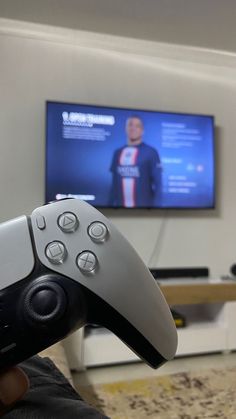 a person holding a video game controller in front of a flat screen tv on the wall