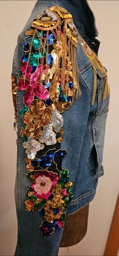 the back of a jean jacket with colorful sequins and chains hanging from it