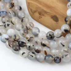 two strands of grey and white glass beads on a wooden stand with a piece of wood in the background