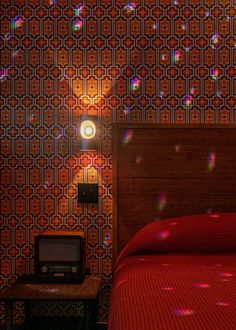 a bedroom with a bed, night stand and wallpaper in the background that has bubbles on it