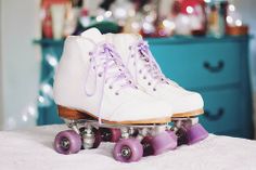 a pair of roller skates sitting on top of a white bed with purple wheels