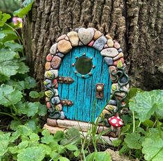 a small blue door sitting in the grass next to a tree